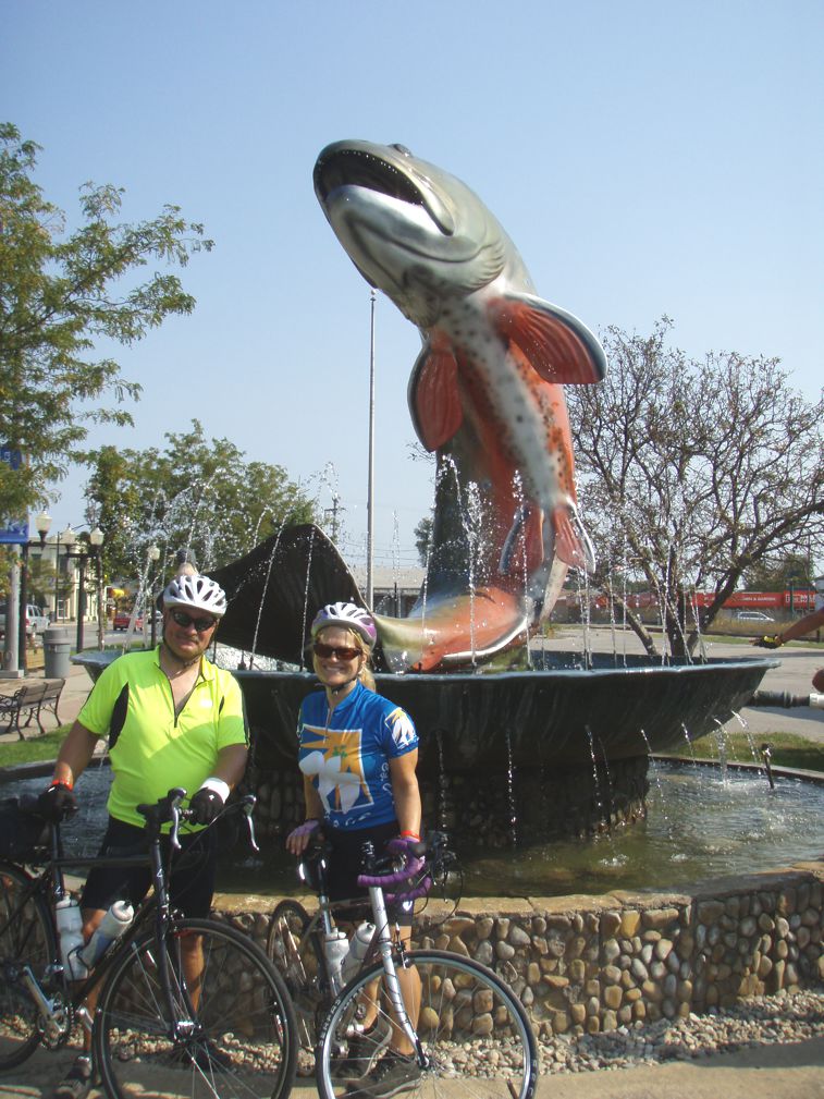 The happy couple with their bikes in front os a salmon fountain